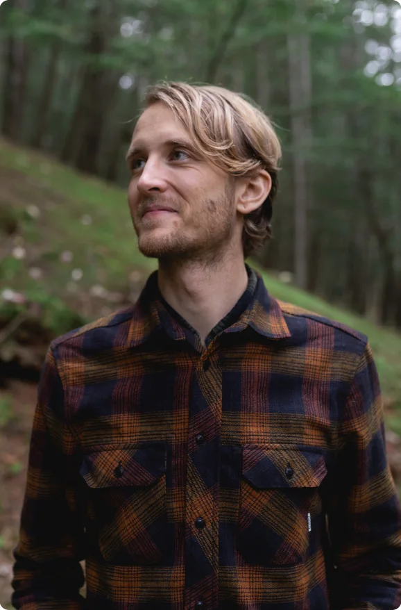 Caleb Copeland outdoors in a wooded clearing, looking off to one side